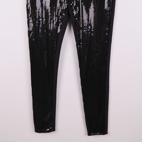 Nedredelen av ben med tättsydda svarta paljetter på tights