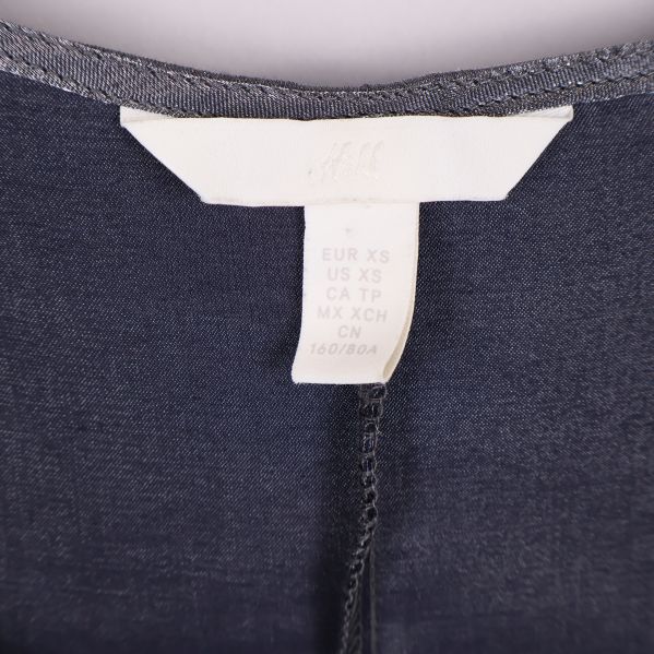 Närbild på storleksetikett med märke H&M och storleksinformation XS