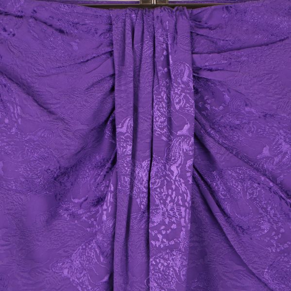Närbild på draperad detalj framtill på lila kjol