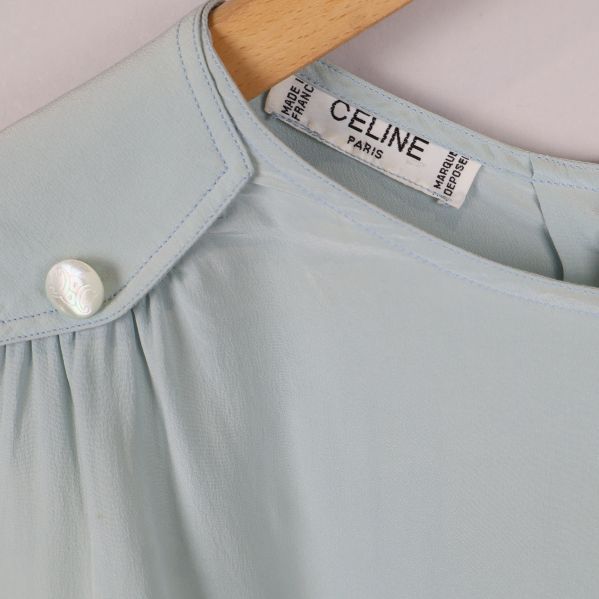 Närbild på axel med pärlknapp och Celine-märke i nacken