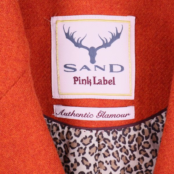 Närbild på blazeretikett med Sand Pink Label-logga