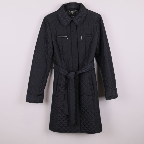 Svart quiltad jacka med skärp framifrån mot vit bakgrund