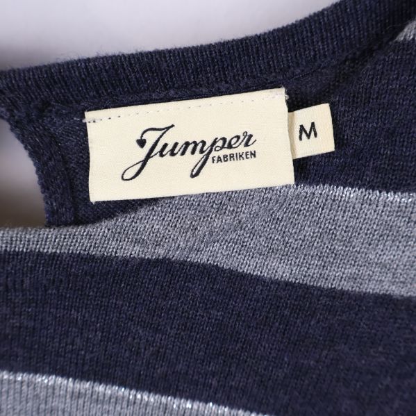 Närbild på etikett Jumperfabriken och storlek M