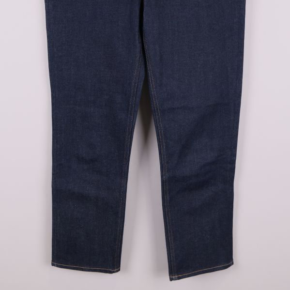 Närbild på benen och fållen av mörkblå jeans