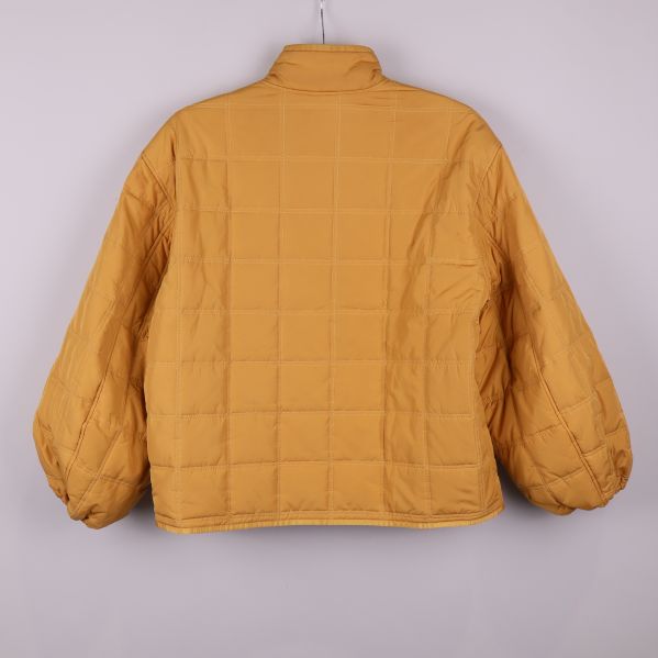 Quiltad jacka i gul nyans fotograferad bakifrån
