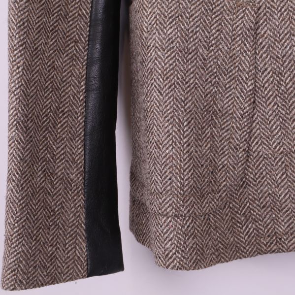 Närbild på blazer med fiskbensmönster och svart skinnärm