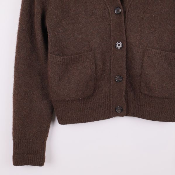 Närbild på fickor och nederdel av brun cardigan