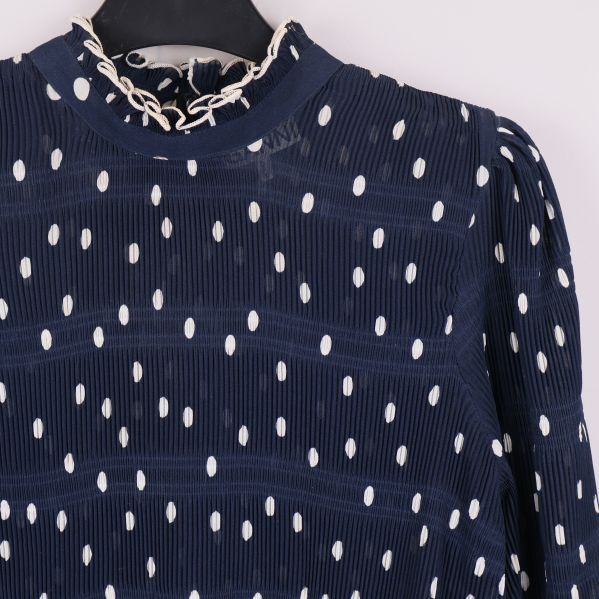 Närbild på krage och övre del av blå prickig blus