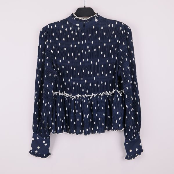Baksida av blå prickig blus med volanger och lång ärm