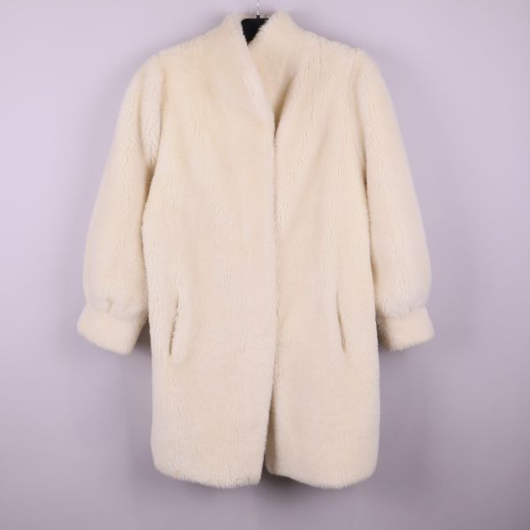 Framsidan av vit pälsliknande vintagekappa med fickor och ärmar