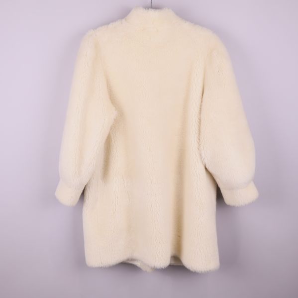 Baksidan av vit luddig vintagekappa med puffärmar