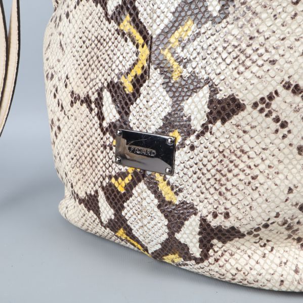 Närbild på väska med ormliknande mönster och logotyp