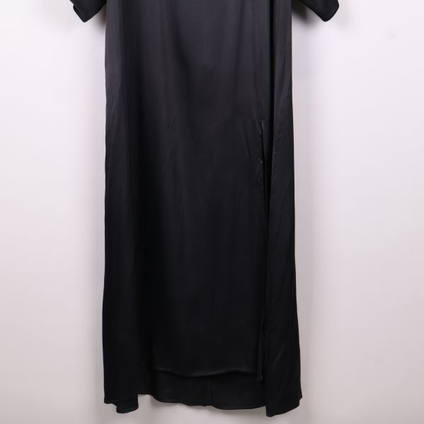 Närbild på nederdelen av svart långklänning med slits