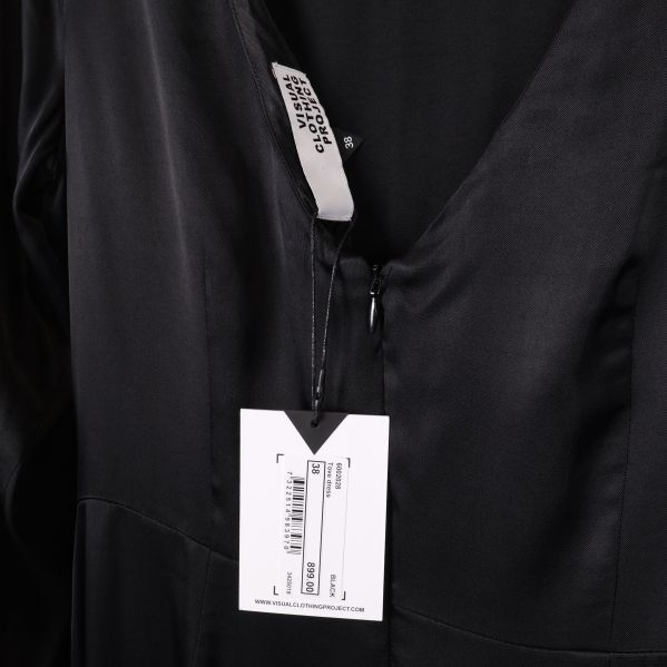 Närbild på klänningens etikett med varumärket Visual Clothing Project