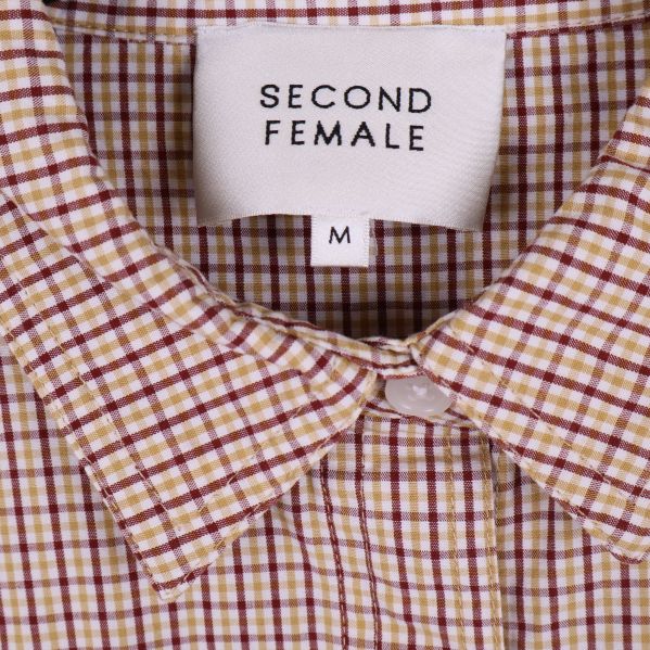 Närbild på kragen med Second Female-märke