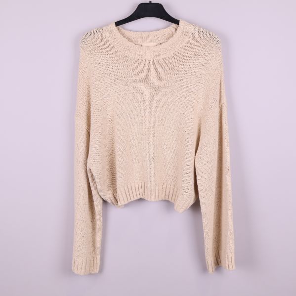 Stickad beige tröja upphängd framifrån