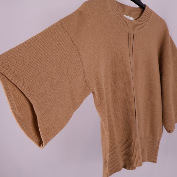 Närbild på ärm och sidosöm på beige stickad tröja