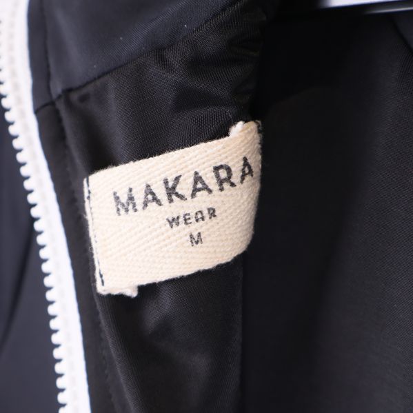 Närbild på etikett med Makara logotyp och storlek M