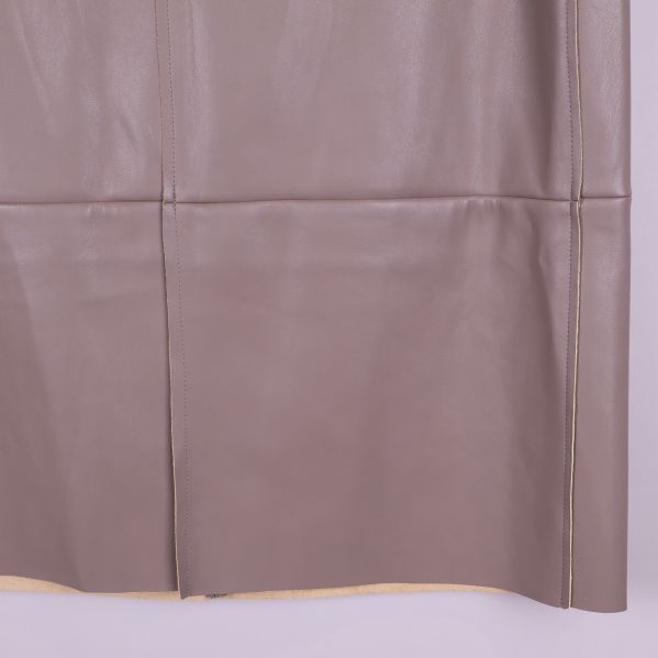 Nedre delen av beige pennkjol i konstläder