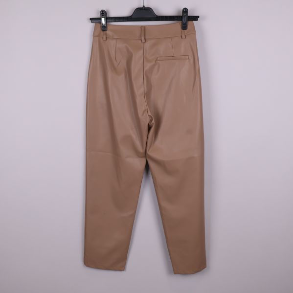 Beiga byxor i skinnimitation upphängda bakifrån