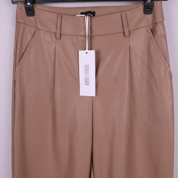 Detaljbild av överdelen och fickor på beiga byxor