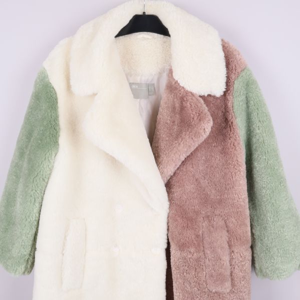 Närbild på kappa i teddy med bred krage och fickdetaljer