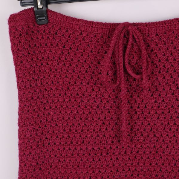 Övre delen av mörkröd stickad kjol med knytband