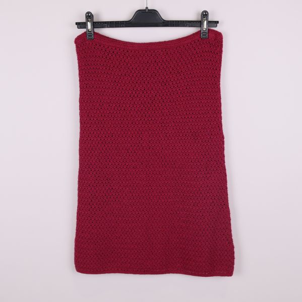 Stickad mörkröd kjol sedd bakifrån mot ljus bakgrund