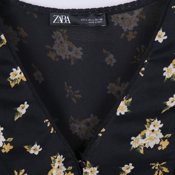 Närbild på ZARA-etikett i blommig svart blus