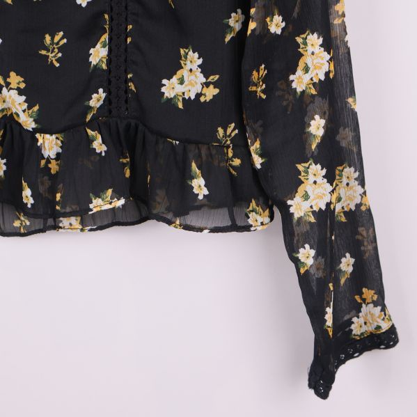 Nederkant och ärmslut med volang på blommig svart blu