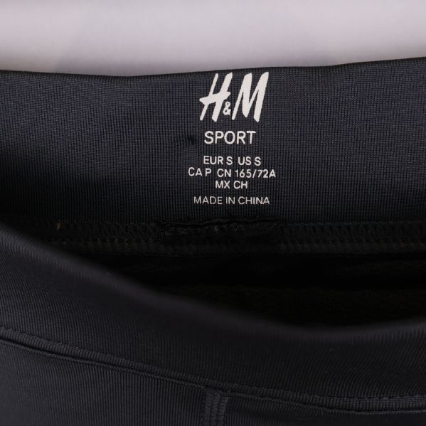 Närbild av H&M Sport logotyp och storleksinformation i linningen