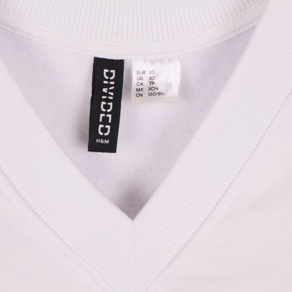 Närbild på v-ringning och inneretikett på vit väst