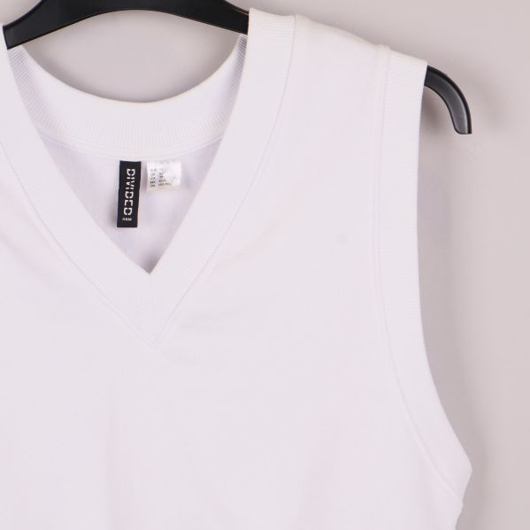 Närbild på axel och v-ringning av vit väst