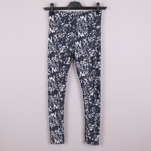 Framsida av svartvita mönstrade träningstights på galge