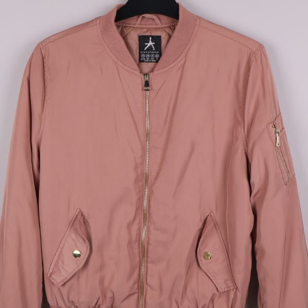 Närbild av fickor och dragkedja på gammelrosa bomberjacka