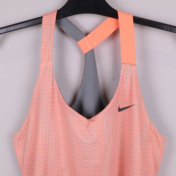 Närbild på axelband och Nike-logotyp på peachmönstrat linne