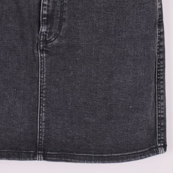 Närbild på nedre delen av svart denimkjol med synliga sömmar