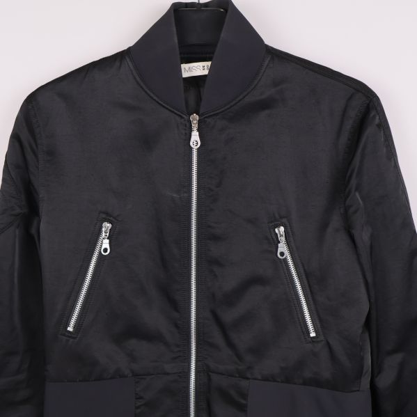 Detalj på jackans silverfärgade dragkedjor och överdel