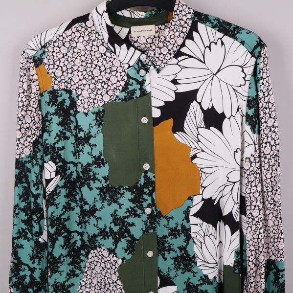 Överkant av blus med stora vita blommor och färgpartier