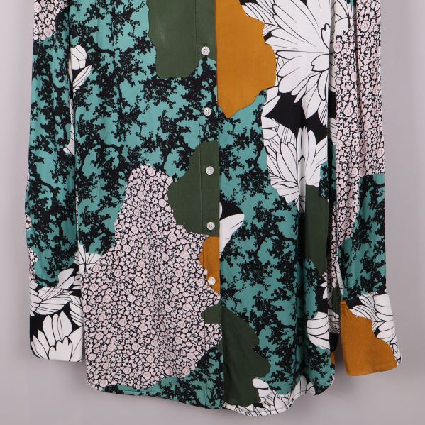 Nedre del av blus med blommotiv och knäppning