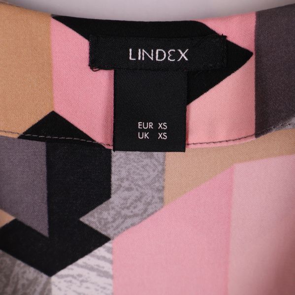 Etikett från Lindex visar storlek XS på mönstrat tyg