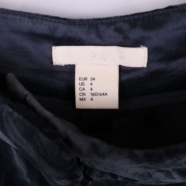 Närbild på storleksetikett för svarta byxor från H&M