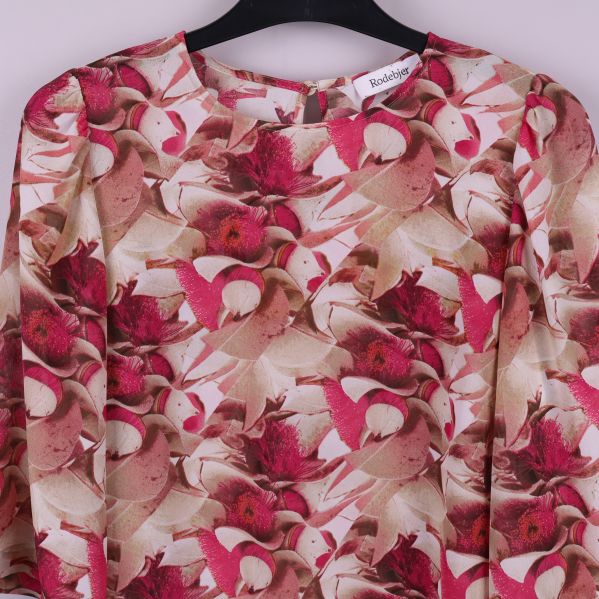 Närbild på blusens framstycke och blommigt mönster