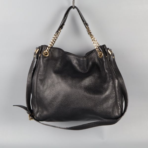 Svart axelremsväska hänger med kedjehandtag synligt