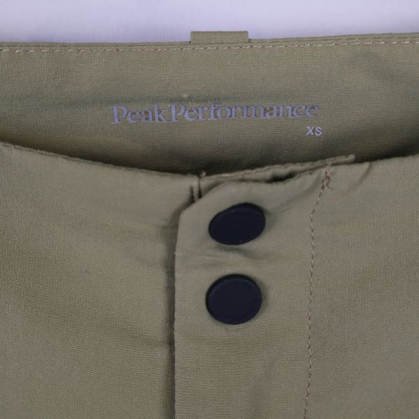 Närbild på Peak Performance-logo och storlek xs på byxlinningen
