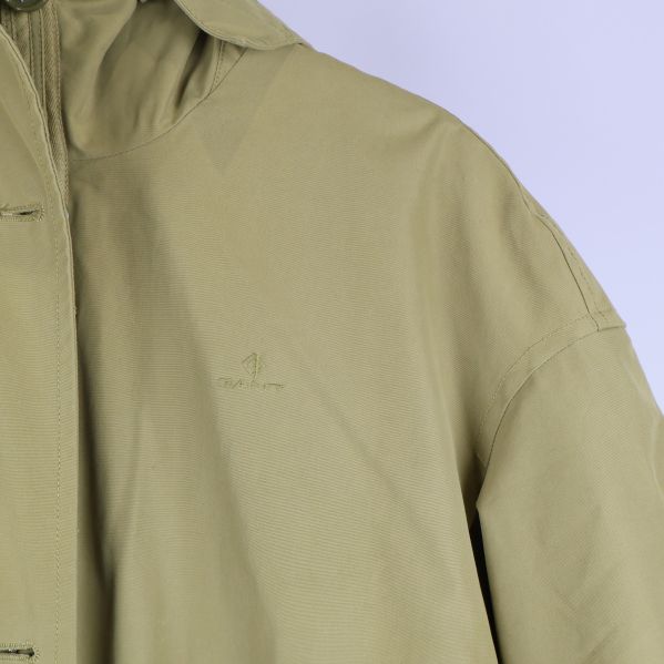 Närbild av parkasens axel och ton-i-ton broderad logga