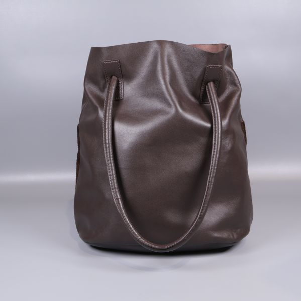 Framsidan av brun bucketväska med dubbla axelband