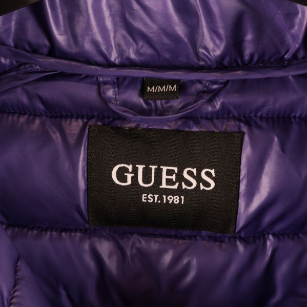 Närbild på svart GUESS-märke på jackans insida