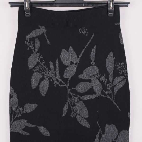 Närbild på midjan av svart kjol med grått bladmönster