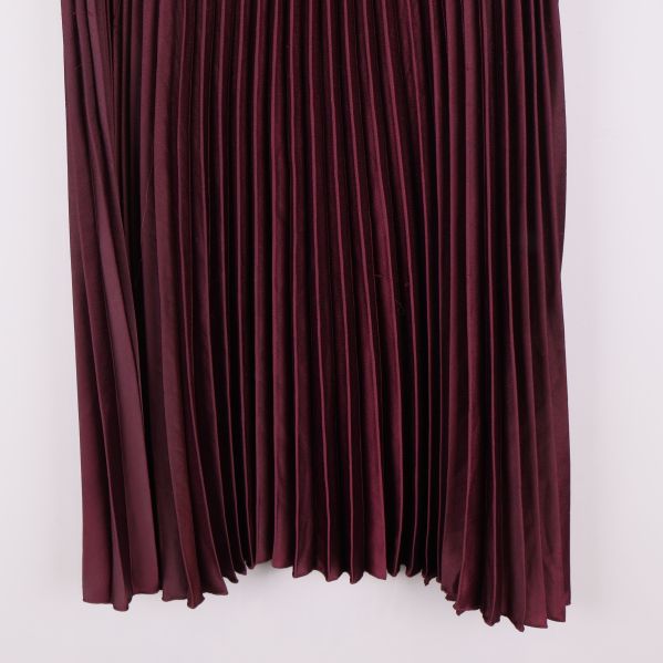 Detaljbild av nedre delen på vinröd plisserad kjol